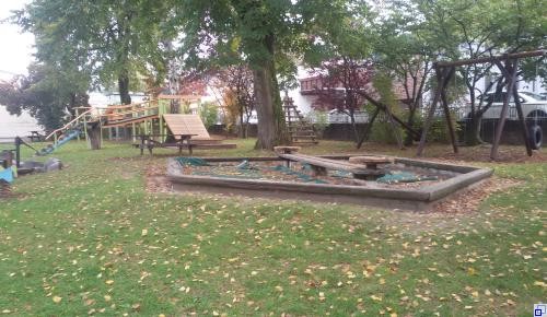 Außenbereich Kindergarten Sternschnuppe Rasenfläche mit Sandkasten und Klettergeräten im Hintergrund