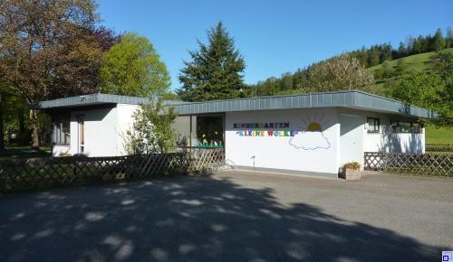 Flachdachgebäude Kindergarten "Kleine Wolke" Parkplatz und weißes Flachdachgebäude mit Logo drauf