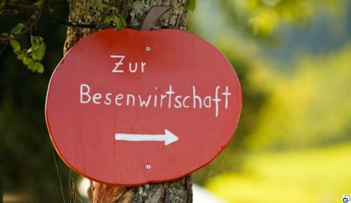 Ein aus Holz geschnitzter Apfel Schild, welches zur Besenwritschaft hinweist