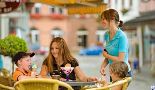 Bedienung von Eiscafe Venezia, die eine Familie mit Eisspezialitäten verwöhnt